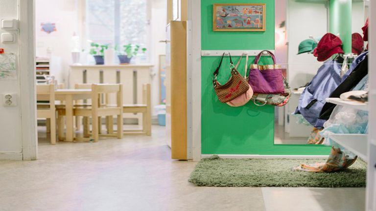 Bild av ett rum på förskolan med stolar och krokar för kläder