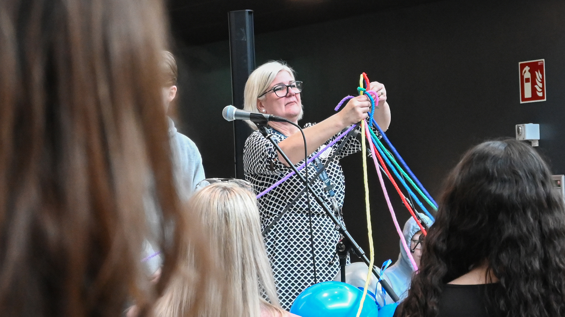En kvinna håller upp flera olikfärgade rep som knutits ihop.