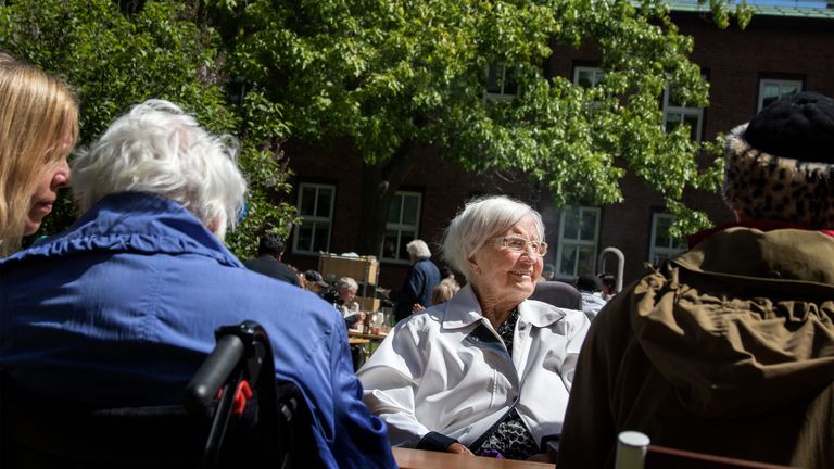 Bild på äldre personer som sitter ute i solen.