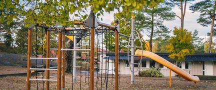 En skolgård med en gul rutschkana och en klätterställning