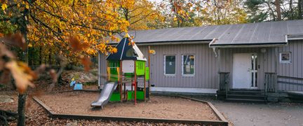 En skolbyggnad med en skolgård med rutschkana framför.