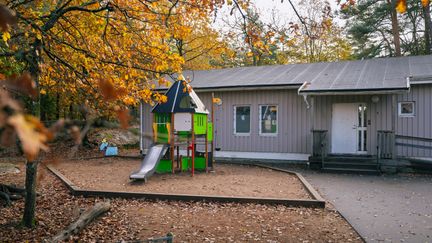 En skolbyggnad med en skolgård med rutschkana framför.