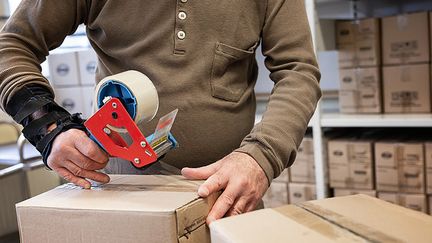 En person klistrar igen en låda med tejp.