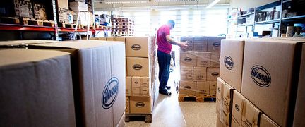 En person står i en lagerlokal där det finns stora kartonger.