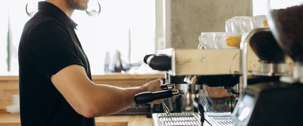 En person gör kaffe med en kaffemaskin.