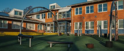 En hinderbana framför Kannebäcksskolan med skolbyggnaden och en innebandyplan i bakgrunden.