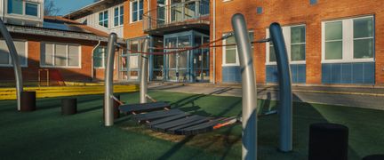 En hinderbana framför Kannebäcksskolan med skolbyggnaden och en innebandyplan i bakgrunden.