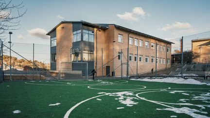 En multiarena med en gul skolbyggnad i bakgrunden.