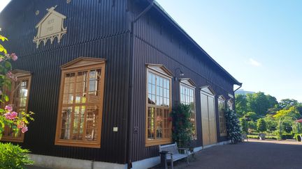 Mörkbrun byggnad i trä med orangea detaljer runt fönster och dörrar.