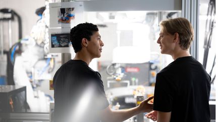 Två elever som samtalar vid en maskin som tillverkar batterier. Foto: Tim Kristensson