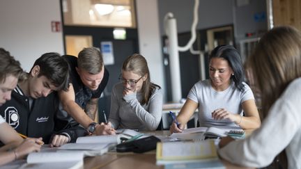 Koncentrerade elever som får hjälp av lärare i klassrummet. 