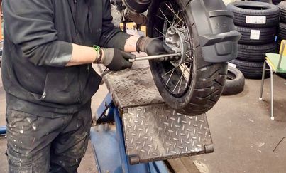 En person arbetar med en moped som är upphissad på en hiss.