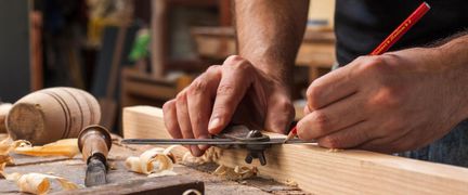 En person ritar på en träbit.