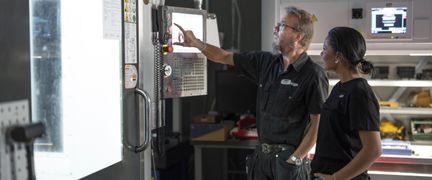 Lärare instruerar elev vid CNC-maskin. Foto: Tim Kristensson