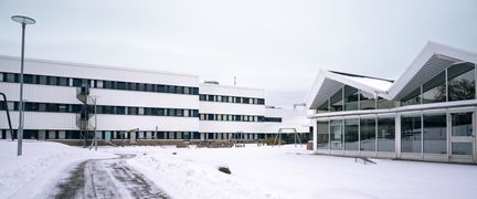 En snötäckt väg framför några av Gårdstensskolans byggnader.