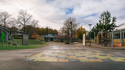 En skolgård i asfalt framför en skolbyggnad.