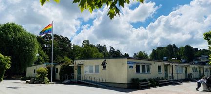Trollängsskolans huvudbyggnad med en pride flagga i bakgrunden.
