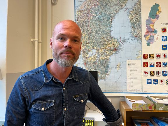 Bilden visar Henrik framför en Sverigekarta. 