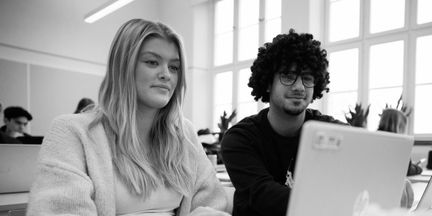 Två elever som tittar på en laptop på en lektion