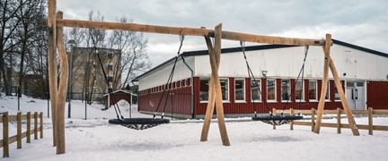 Ett par gungor framför Tretjärnsskolan med en av skolans byggnader i bakgrunden.