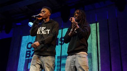 Två unga personer med mikrofoner på en scen