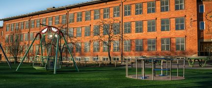 En lekplats utanför Kärralundsskolan med en gunga och en karusell.