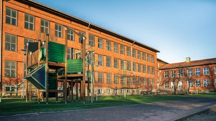 En lekplats utanför Kärralundsskolan med en klätterställning och en rutschkana. Några skolbyggnader kan ses i bakgrunden.