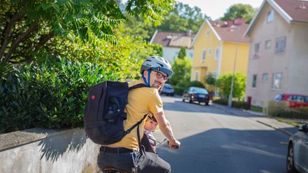 En man och ett barn på cykel på en villagata