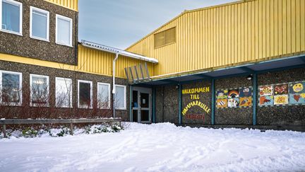 En skolbyggnad med mosaikkonst och texten Välkommen till Hammarkulleskolan på fasaden.