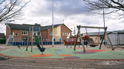 En skolgård med gunga, rutschkana och lekskepp.