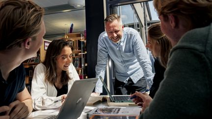 Lärare som pratar med en grupp elever i ett klassrum. 