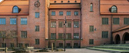 En stor skolbyggnad i rött tegel med en klocka på fasaden.