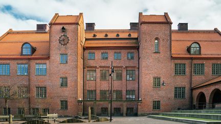 En stor skolbyggnad i rött tegel med en klocka på fasaden.