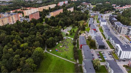 Översiktsbild på Svartedalen med hus, gräsmattor, träd och människor.