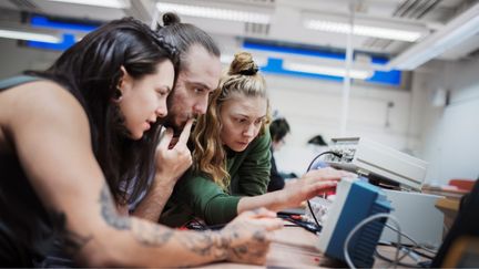 Tre elever sitter med elkopplingar och samarbetar.