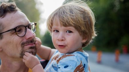 En närbild på en pappa som håller sitt barn i famnen.