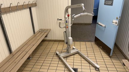 En flyttbar taklift står i ett omklädningsrum.