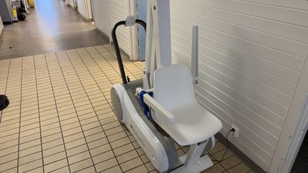 En gråvit lift med handtag och sits. 