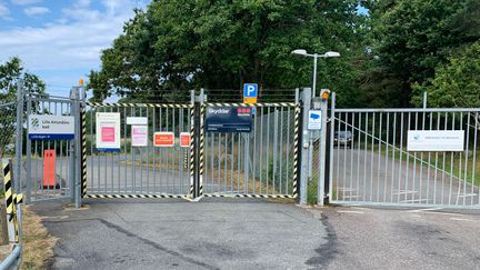 Två breda grindar på en bilväg. Många olika skyltar på grindarna.