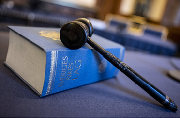 Lagboken ligger på ett bord med en domarklubba över den.