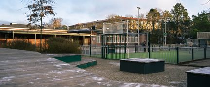 En skolgård med en multiarena framför en skolbyggnad i tegel.