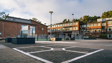 En skolgård framför en skolbyggnad i tegel.