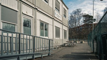 En ramp och en bänk framför en grå skolbyggnad