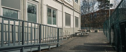 En ramp och en bänk framför en grå skolbyggnad