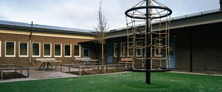 En skolgård med en lekställning och en skolbyggnad i bakgrunden.