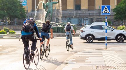 Tre personer cyklar upp mot poseidon, Götaplatsen i Göteborg.
