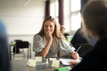 Elev som sitter i ett klassrum och antecknar. Foto av Valentin Experience