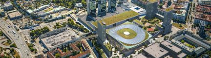 Flygbild över arenakomplex med höghus och grästak