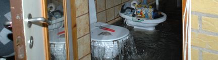 Översvämmade villa i Åkarp i Skåne. Vatten forsar ur toalettstolen trots att toalettlocket är stängt. På golvet flyter vatten.