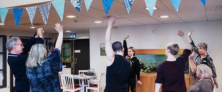 En grupp gör gymnastik i en lokal med vimplar i taket.